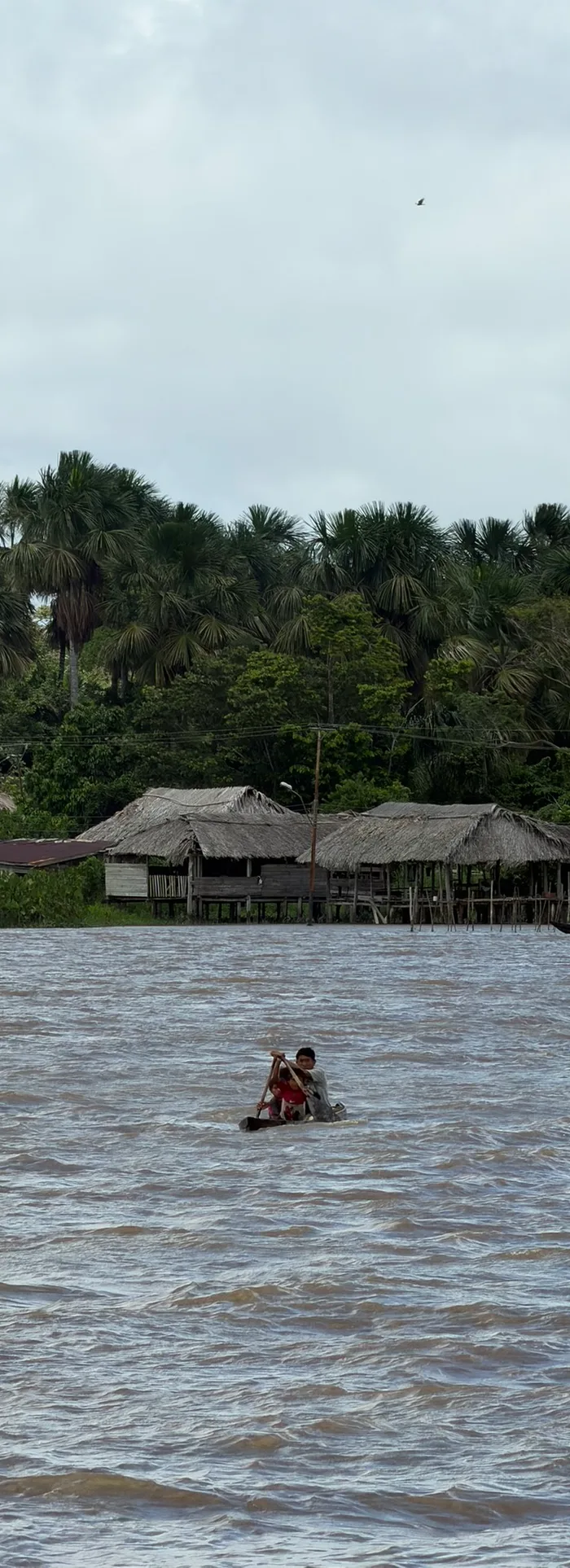 Dos niños reman una canoa en el río frente al caserío Warao